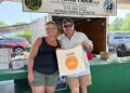 A man and woman pose for a photo at a farm stand at the Electric City Farmers Market in Scranton, PA.