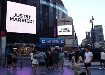 People watch giant screens showing the message "JUST&T MARRIED!" (T&T for Taylor and Travis) outside Madison Square Garden, the reported venue for the wedding celebrations of pop singer Taylor Swift and pro-athlete Travis Kelce, in New York City on July 3, 2026.