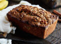 Loaf of walnut banana bread on rack next to knife