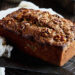 Loaf of walnut banana bread on rack next to knife