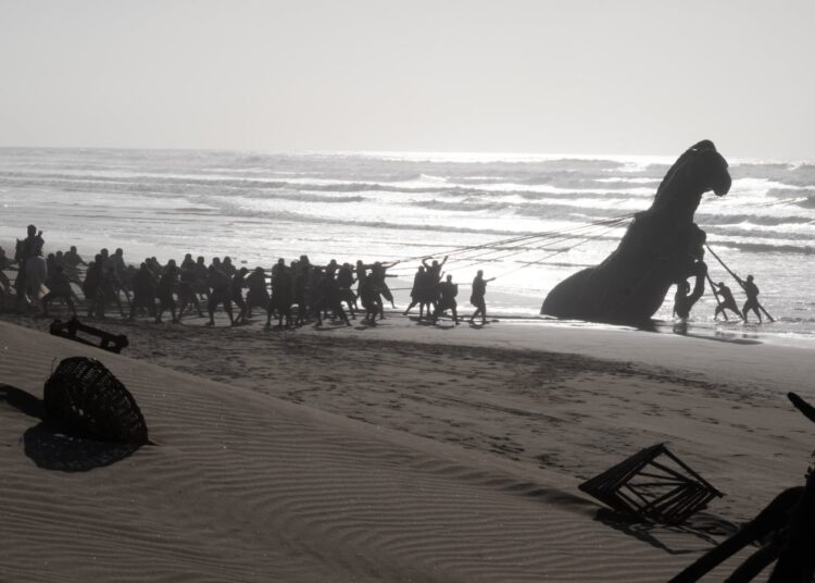 Soldiers drag the Trojan Horse out of the sea.