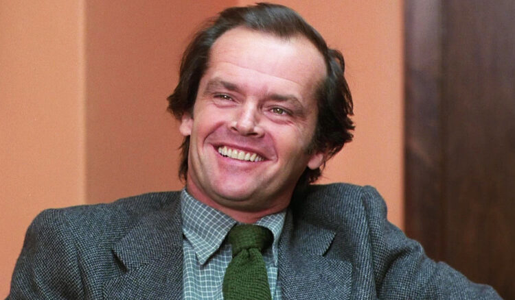 Jack Nicholson's Jack Torrance smiles as he sits in an office in The Shining