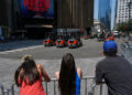 People watch as trucks are unloaded at Madison Square Garden, in New York City