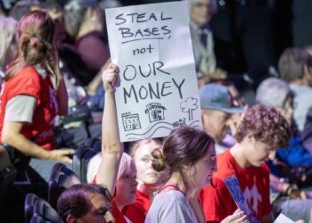 A member of Stand Up KC holds up a sign during a presentation about the proposed rezoning of Crown Center for a new Kansas City Royals ballpark at the Regnier Theatre inside Union Station on Monday, July 27, 2026, in Kansas City.