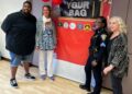 Policiais, parceiros comunitários, dão material escolar, evento de anfitrião que incluía música, comida, cortes de cabelo