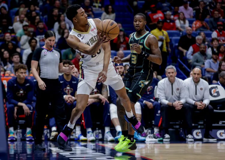 O armador do New Orleans Pelicans, Trey Murphy III (25), salva a bola enquanto o Charlotte Hornets guarda ...
