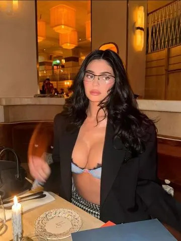 Kylie Jenner não usa nada além de um micro-sutiã como uma blusa com o visual codificado por sirene do escritório