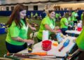 Os membros da equipe do Commerce Bank limpam e classificam o doado de equipamentos de beisebol e softball em 28 de agosto.