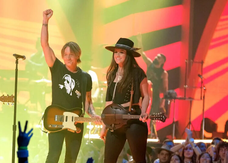 O guitarrista de Keith Urban, Maggie Baugh Misses Concert, enquanto mostra a foto de Nicole Kidman durante a apresentação de slides emocional