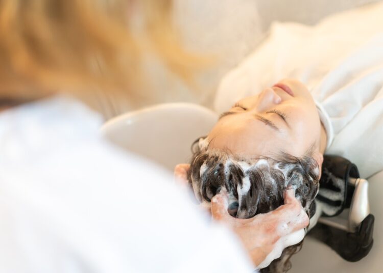 Cabeleireiro lavando o cabelo na mesa de shampoo