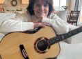 Shawna Edwards - compositora de "Porque," uma nova adição aos Hinos — Para o Lar e a Igreja — posa para uma foto com um violão em Lehi, Utah, janeiro de 2025.