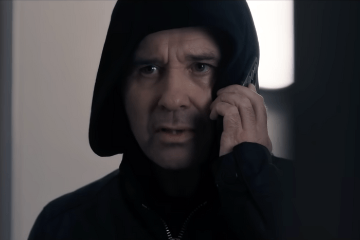 Andrew Scarborough como Graham Foster em um moletom preto e ao telefone em Corriedale.