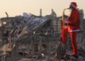 Pai e filho se vestem de Papai Noel e visitam a cidade de tendas de Gaza com presentes e música para celebrar o Ano Novo