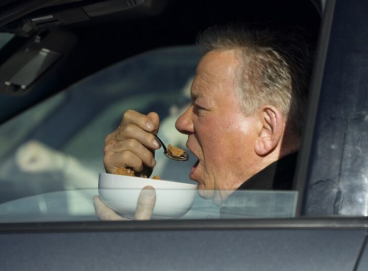 William Shatner fotografado comendo uma tigela de cereal em seu carro no semáforo