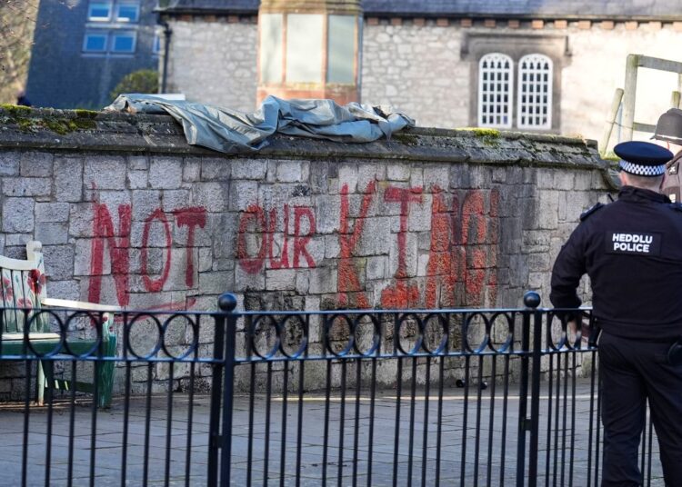 Trabalhadores correm para limpar o grafite 'Not Our King' da catedral antes da visita de Charles