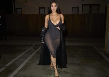 Kim Kardashian usa um vestido bodycon preto e sapatos de salto alto com cordões para comemorar o novo pop-up