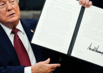 President Donald Trump holds up a signed executive order in the Oval Office on April 18, 2026.