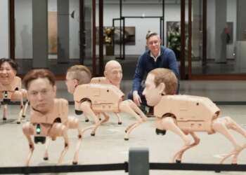 Artist Beeple, Mike Winkelmann, poses inside his installation titled "Regular Animals," with robots in the likeness of Kim Jong Un, left, Elon Musk, second from left, Jeff Bezos, center, and Mark Zuckerberg, right, at the Neue Nationalgalerie museum in Berlin, Germany.