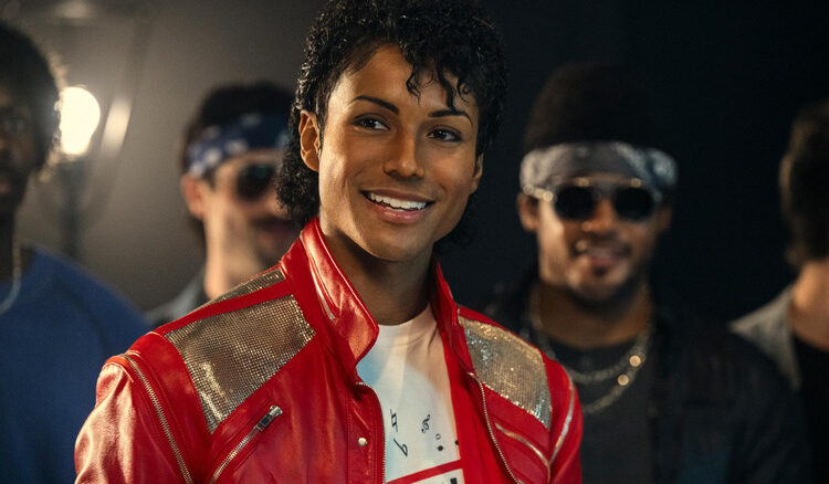 Jaafar Jackson como Michael Jackson sonriendo con su chaqueta roja en la película biográfica de Michael