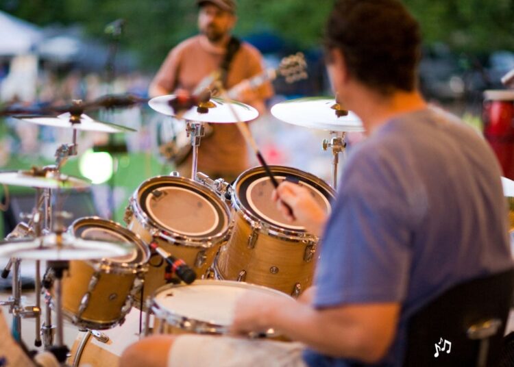 Baterista y guitarrista en un concierto de rock en el parque.