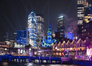 Una proyección de luz brilla sobre la torre del reloj y el horizonte de la ciudad de Sydney.
