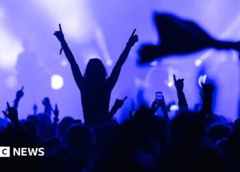 A cut out photo of a grey haired David Attenborough looking at the camera, wearing a blue shirt and shown from shoulder up. Behind him is a graphic design of a green arc against a baige background with pink mountains and leaves, and flying green birds
