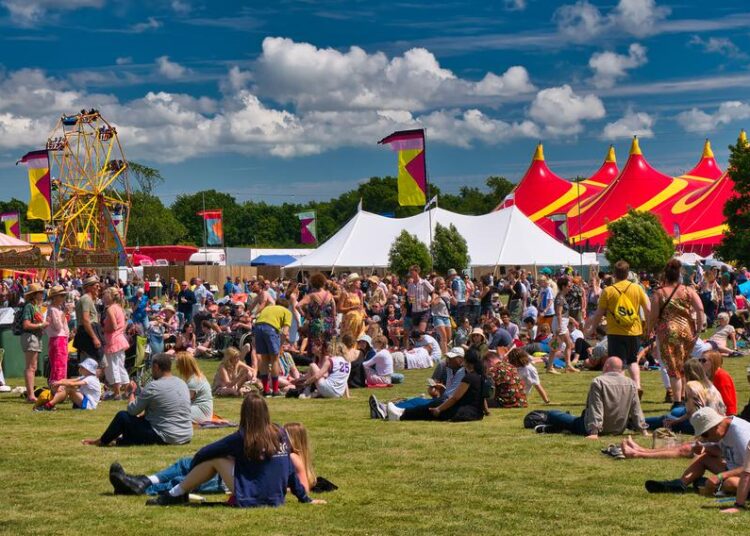 A large crowd at an outdoor summer music festival and fair.