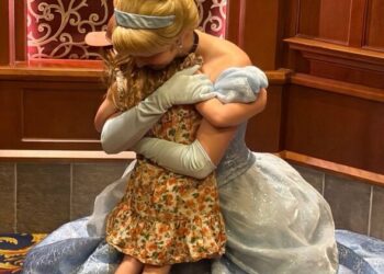 Un individuo vestido con un disfraz de Cenicienta abraza a otra persona, sus rostros oscurecidos por el ángulo de la imagen. Ambos