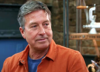 John Torode fotografiado en la serie 19 de Masterchef, con una camiseta naranja