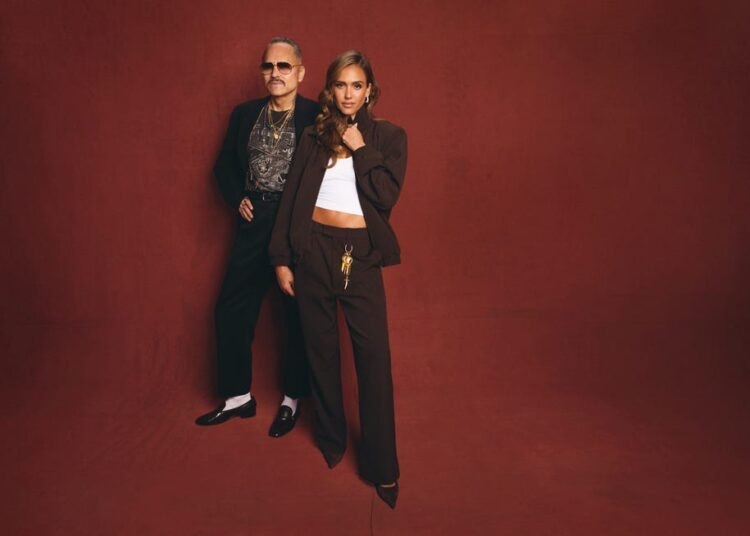 Dos personas con trajes elegantes sobre un fondo rojo.