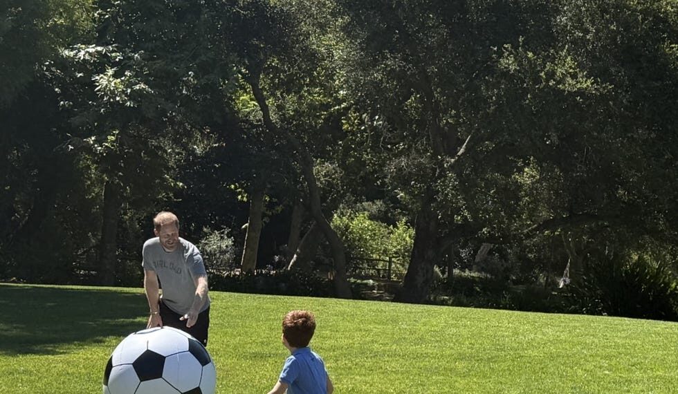 Dos personas jugando con una pelota de fútbol gigante en un campo de hierba.