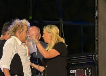 Rod Stewart receiving oxygen from a crew member during a concert.