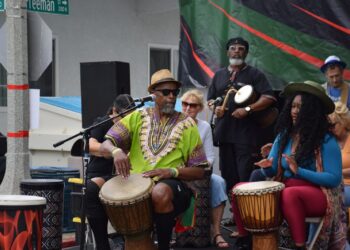People play drums at an outdoor event.