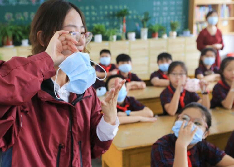 A primary school teacher shows her students how to properly wear a mask in Lianyungang city, eastern China's Jiangsu Province, on August 30, ahead of the official start of the new semester on September 1. On Friday, China's health authorities announced that the country's Delta variant outbreak has been