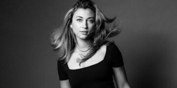Martina Myskohlid faces the camera wearing a black dress, with her hair in motion.