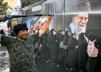 Las personas son rociadas con agua para refrescarse durante el calor mientras hacen cola para recibir comida en su camino a la Gran Mosalla en Teherán el 5 de julio de 2026, para las ceremonias fúnebres del asesinado líder supremo de Irán, el ayatolá Ali Jamenei. — Foto AFP