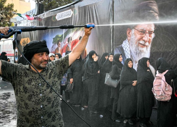 Las personas son rociadas con agua para refrescarse durante el calor mientras hacen cola para recibir comida en su camino a la Gran Mosalla en Teherán el 5 de julio de 2026, para las ceremonias fúnebres del asesinado líder supremo de Irán, el ayatolá Ali Jamenei. — Foto AFP